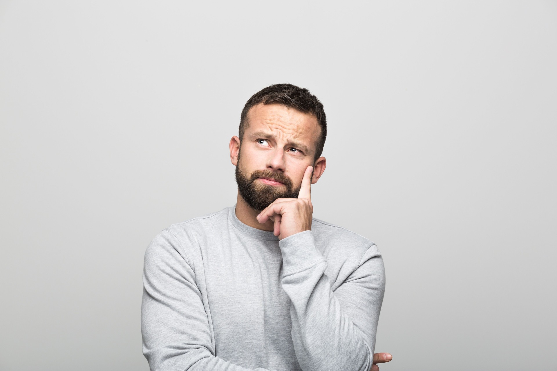 Portrait of pensive bearded young man, grey background